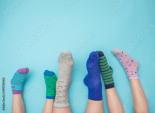Feet of mothers and children with socks in different colors on a light blue background. Family concept. Support and awareness of people with Down syndrome. March 21. Copy space.