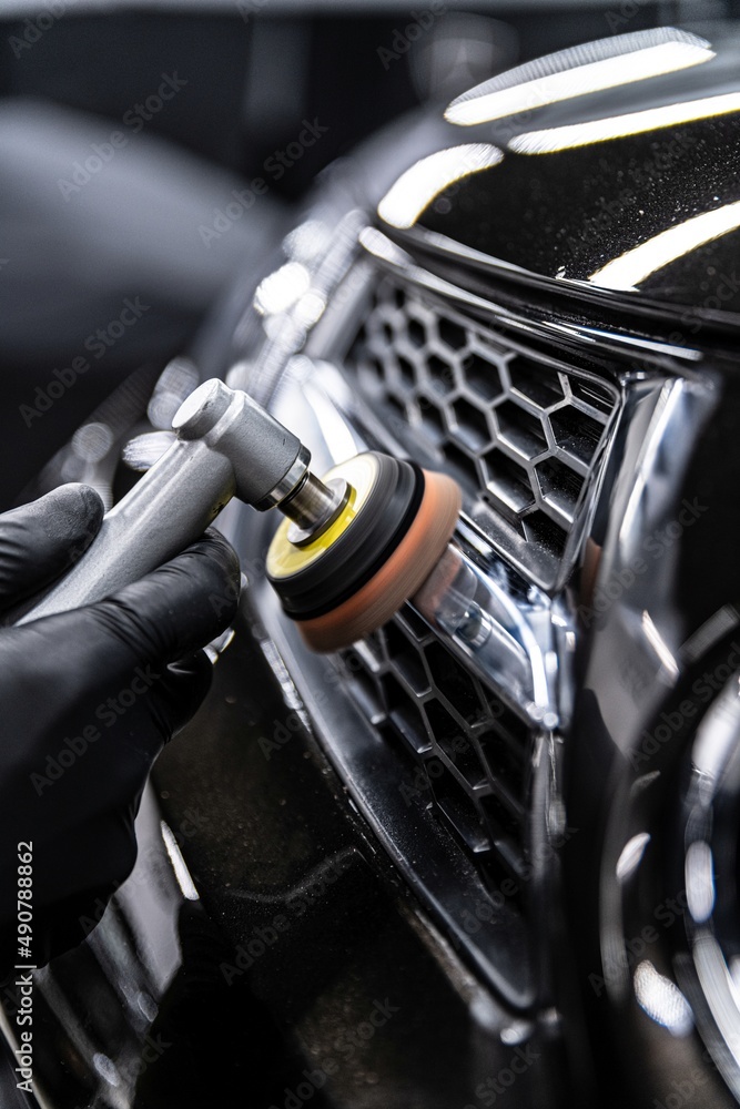 Car detailing technician polishing chrome shine decor on car with eletric polisher