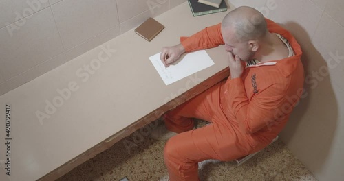 seriously ill prisoner writes a letter in a prison cell.