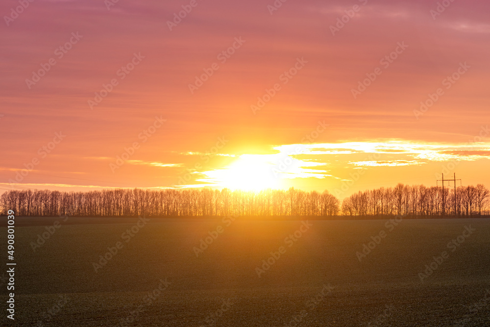 Sunset, sunbeams shining through the trees in the distance, autumn landscape Sunset, sunbeams shining through the trees in the distance, autumn landscape
