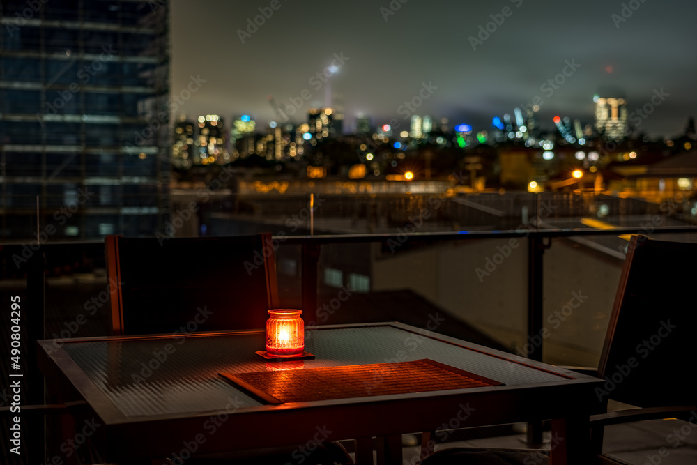Lonely candle lit on the balcony table with a blurred city in the background, Brisbane, Australia Lonely candle lit on the balcony table with a blurred city in the background, Brisbane, Australia