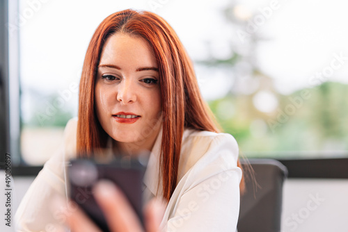 Young woman using mobile phone while working at home © A&NStudio