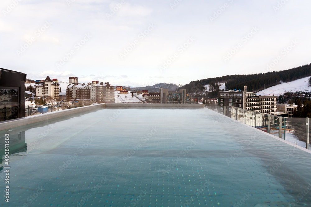 Snow falling on pool at the winter mountains. Winter resort with swimming pool