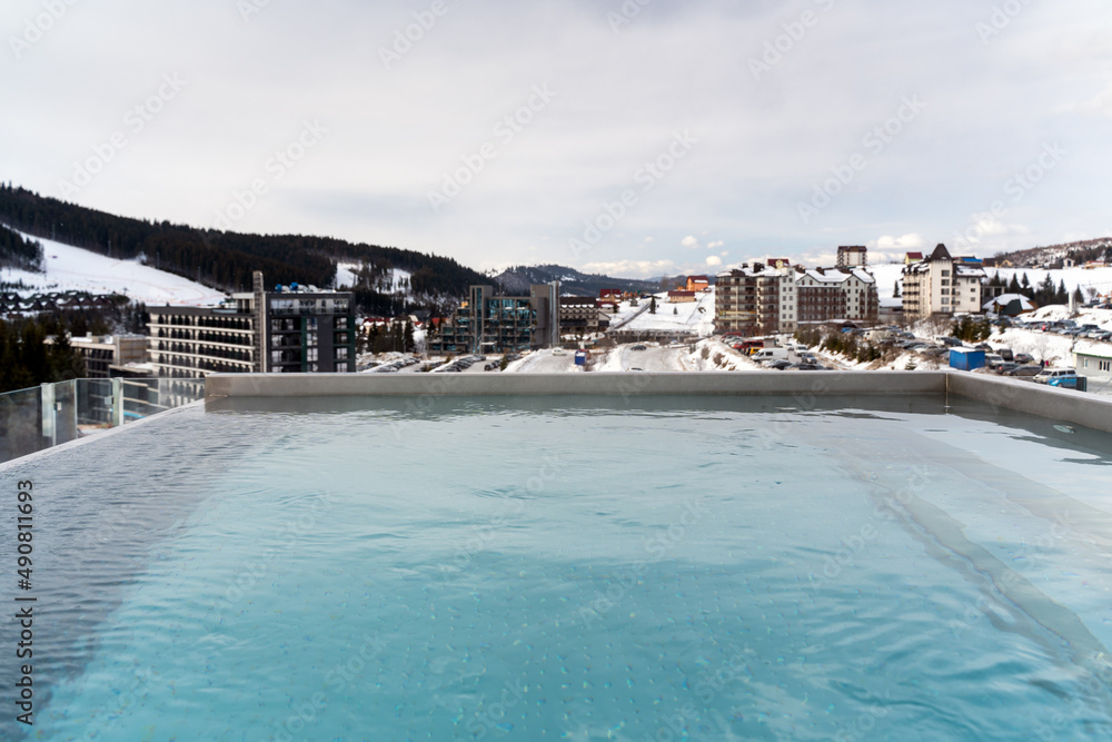 Fototapeta premium Outdoor swimming pool with scenic view of mountains, cloudy weather time. Pool with mountains
