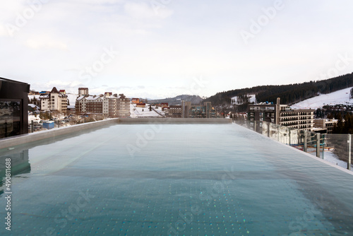 Snow falling on pool at the winter mountains. Winter resort with swimming pool