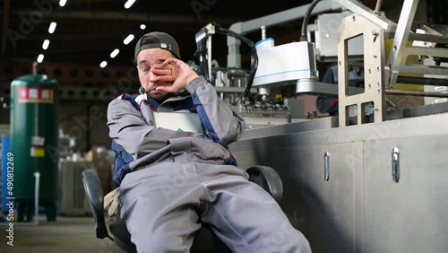 A tired worker violates safety rules and regulations at work and sleeps in the workplace, sometimes waking up from sleep. Overworked worker fell asleep at workplace