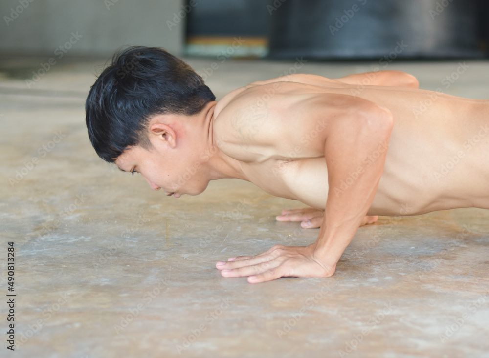 Young Asian men are exercising by doing push-up moves to build healthy and healthy muscles.