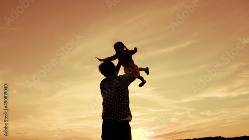 silhouette father with little child daughter sky background. kid girl flies with outstretched arms. childhood dream becoming superhero. kid child baby with dad together. happy family. fun holiday.