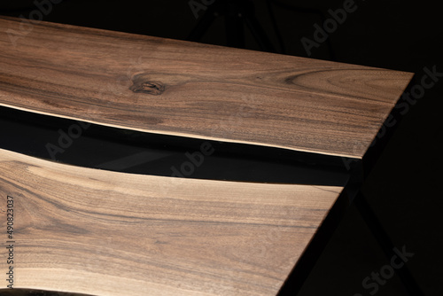 Expensive vintage furniture. The table is covered with epoxy resin and varnished. Luxury quality wood processing. Wooden table on a dark background. Black river made of epoxy resin.