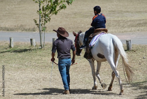Cowboy man rides child on horse 