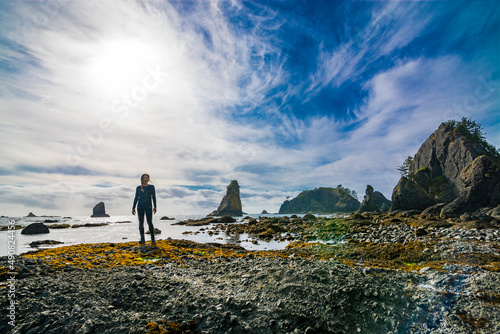 Adventurous athletic woman standing on a rugged Pacific Northwest beach.