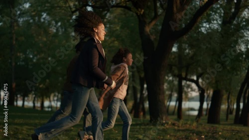 Parents daughter running holding hands golden sunlight. Caring people together. photo