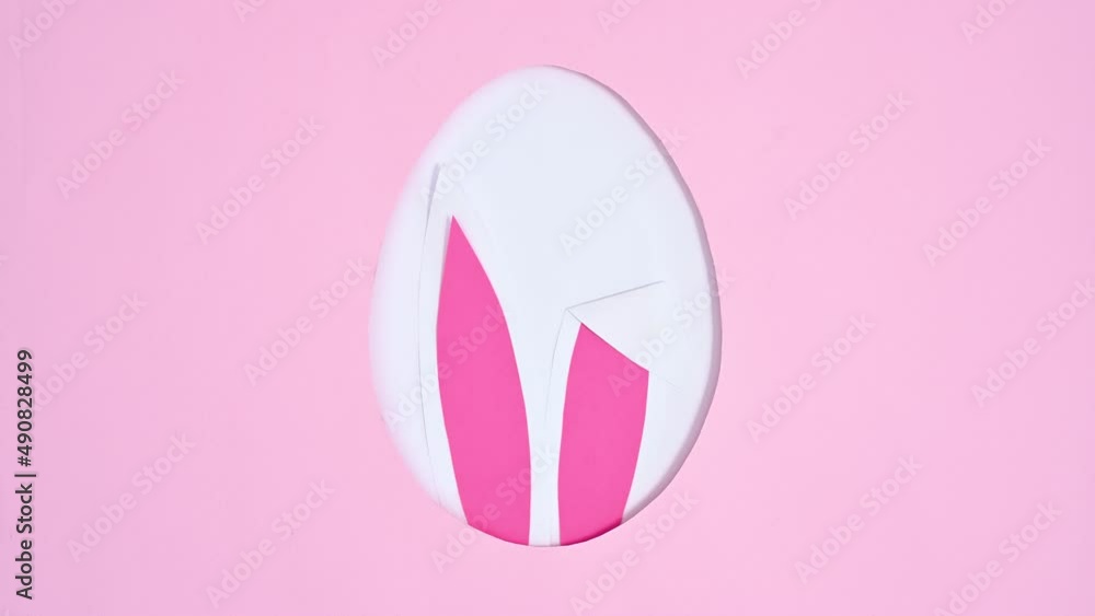 Rabbit ears appear in egg shape on bright pink background. Stop motion flat lay Rabbit ears appear in egg shape on bright pink background. Stop motion flat lay