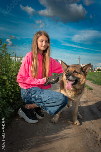 Portrait of a young beautiful girl in a field with a dog. © shymar27