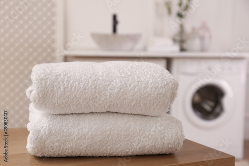 Clean folded towels on wooden table in laundry room