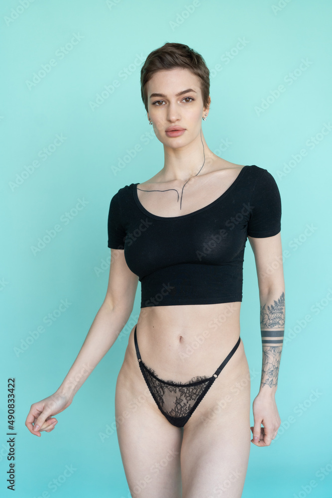 young beautiful woman posing in black lingerie in the studio, stands near the blue wall young beautiful woman posing in black lingerie in the studio, stands near the blue wall
