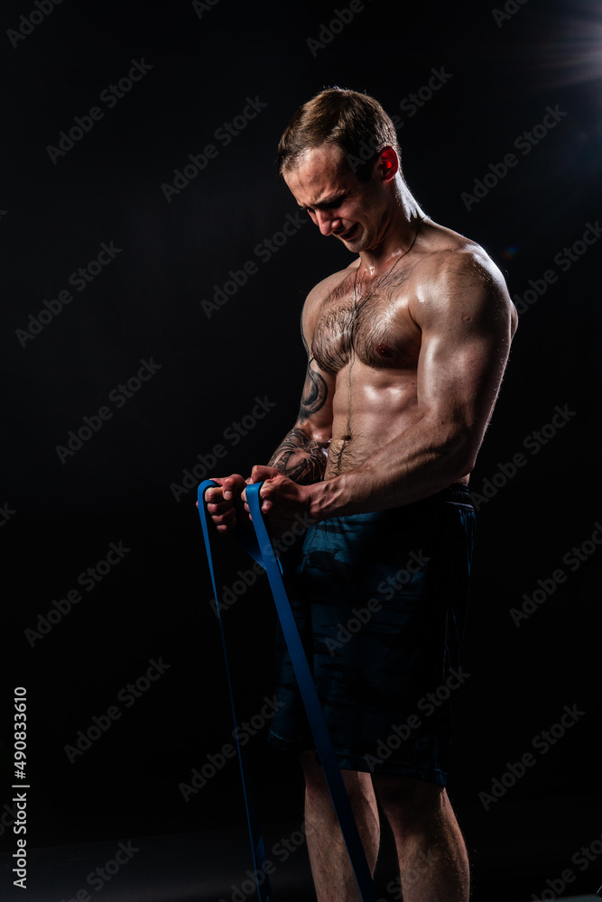 Man on black background keeps dumbbells pumped up in fitness bodybuilding biceps torso, body exercise athletic healthy weightlifting. Young skin metal, gym fit With a ribbon in hand Man on black background keeps dumbbells pumped up in fitness bodybuilding biceps torso, body exercise athletic healthy weightlifting. Young skin metal, gym fit With a ribbon in hand