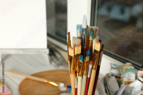 Many different paintbrushes near window, closeup view