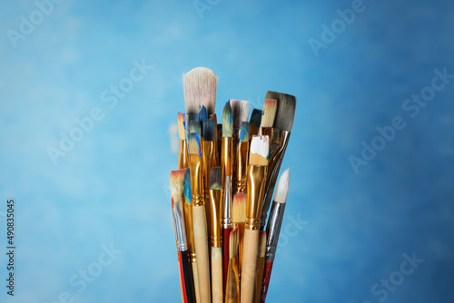 Many different paintbrushes on light blue background