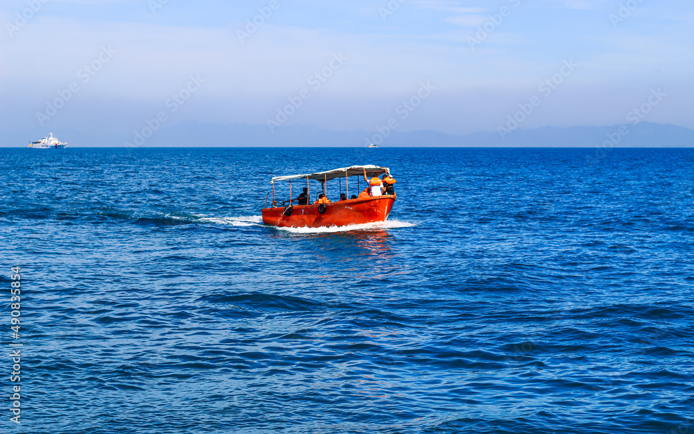 Small tourist boat with passengers. Beautiful seascape with a tourist boat.
