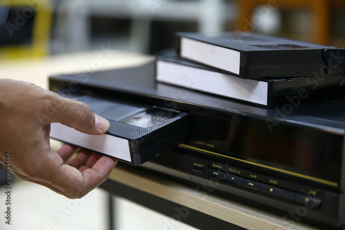 Tableau sur toile Close-up hand put or insert video cassette tape VHS old retro style on video record playback concept of vintage electric and electronic appliances multimedia player device old fashioned