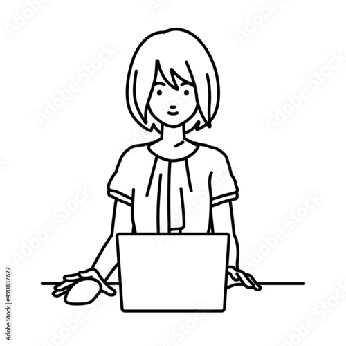デスクで座ってPCを使っているオフィスカジュアルの女性