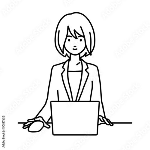 デスクで座ってPCを使っているスーツの女性