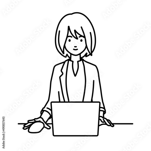 デスクで座ってPCを使っているジャケットの女性