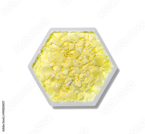 Sodium sulfide flakes in hexagonal molecular shaped container on white background. photo