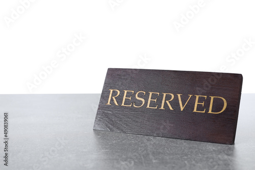 Elegant wooden sign Reserved on grey table against white background, space for text