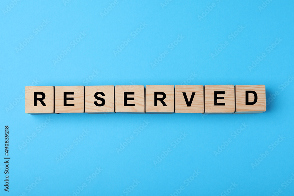 Wooden cubes with word Reserved on light blue background, flat lay Wooden cubes with word Reserved on light blue background, flat lay
