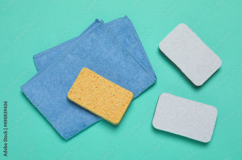Three color sponges and cloth on turquoise background, top view Three color sponges and cloth on turquoise background, top view