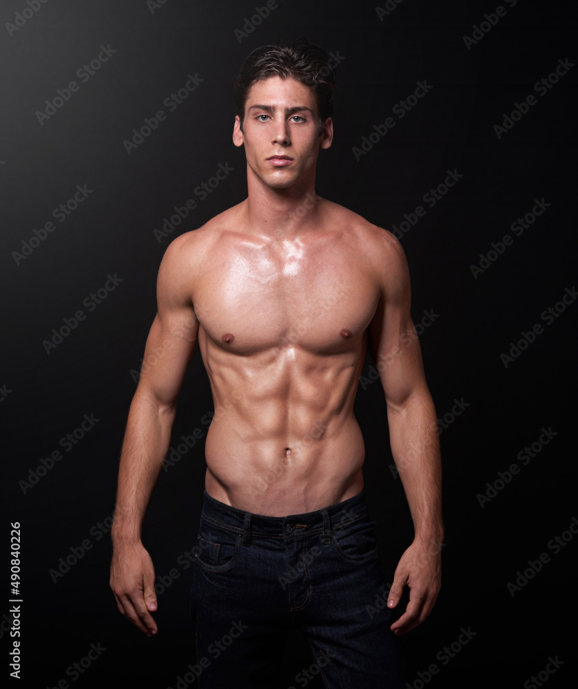I make muscles not excuses. Studio shot of a handsome bare-chested young athlete standing against a black background. I make muscles not excuses. Studio shot of a handsome bare-chested young athlete standing against a black background.