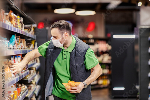 A supermarket worker exposing groceries on aisle during covid 19.