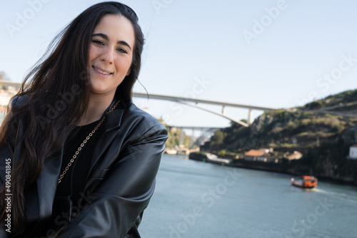 Selfie young woman in a city overlooking river and bridge .