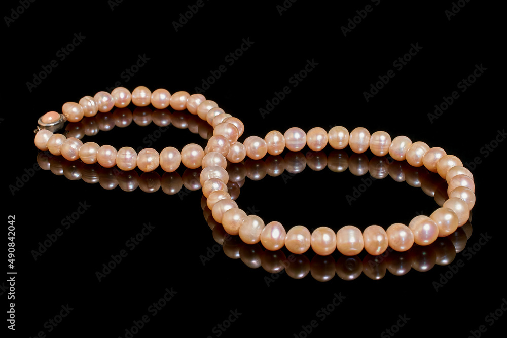 Pink pearl necklace on black background with reflection
