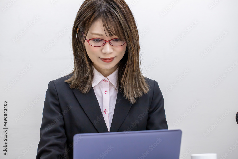 笑顔でパソコン入力をする眼鏡をかけた女性