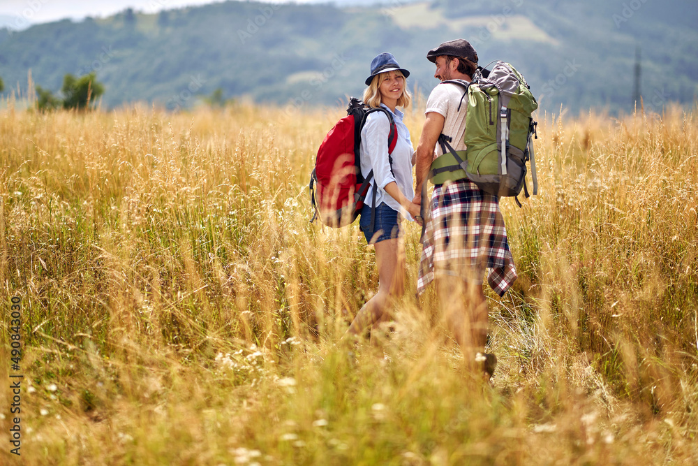 couple is hiking in mountain.Joyful man and woman  at meadow on sunny summer day