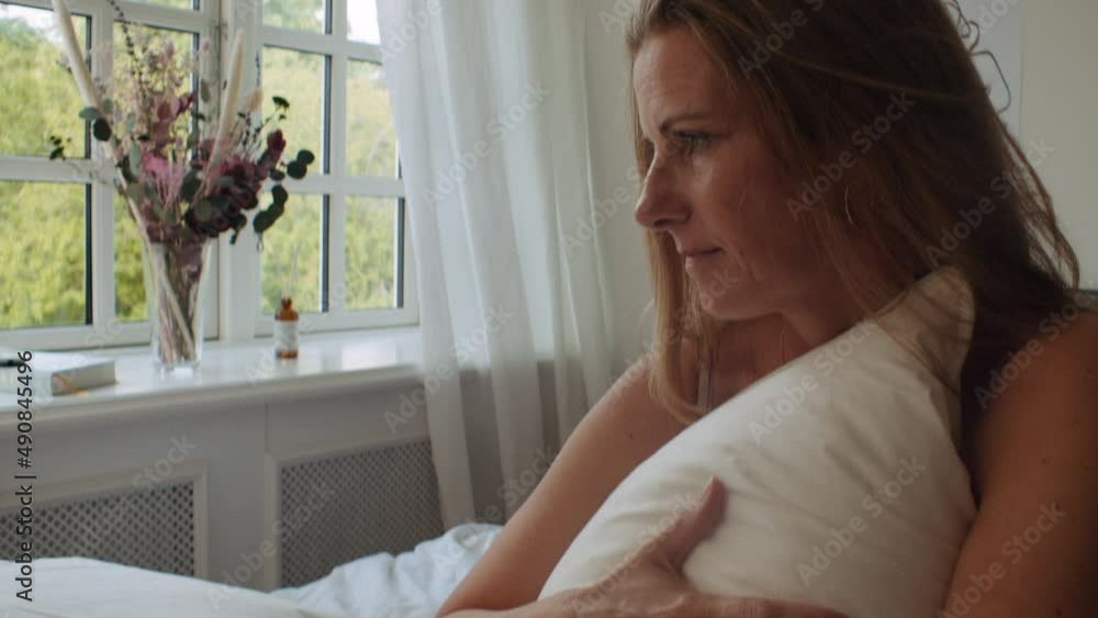 Woman Clutching Pillow On Bed In Morning And Looking Away