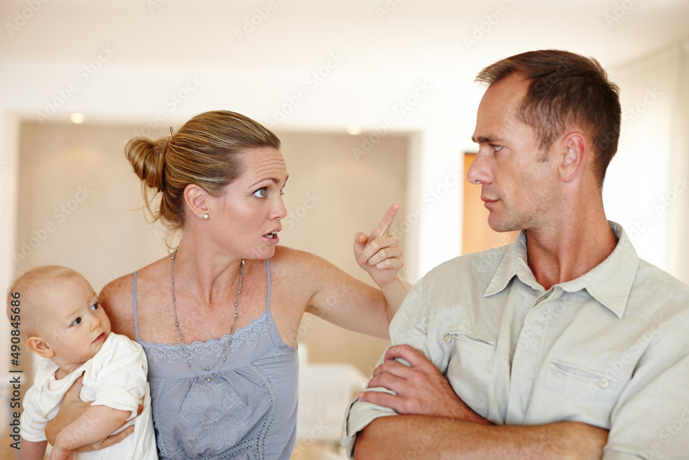 Wasnt me. A couple having an argument while standing in their home with their baby. Wasnt me. A couple having an argument while standing in their home with their baby.