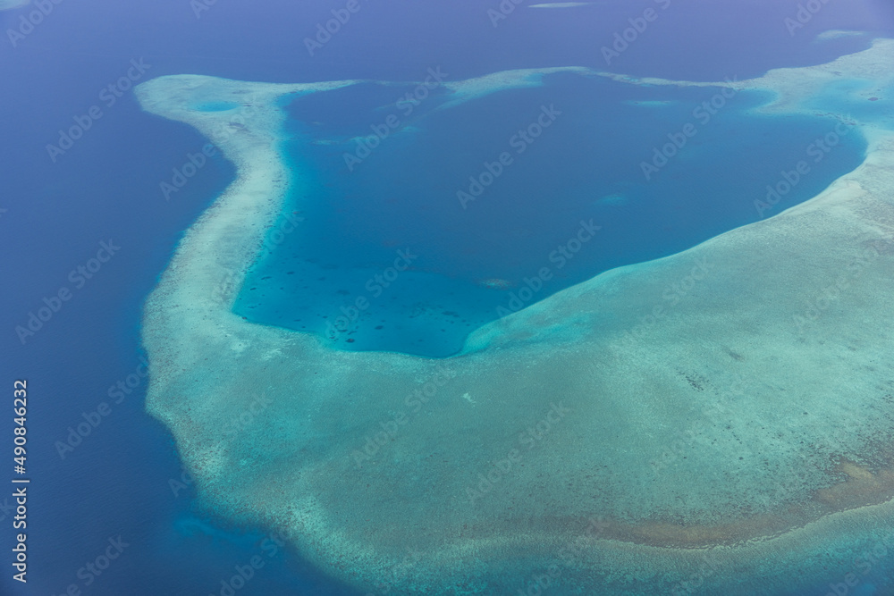 Fototapeta premium Tropical islands and atolls in Maldives from aerial view. Famous travel destination and luxury vacation or summer holiday concept. Aerial landscape of blue sea and resorts, hotels. Gorgeous nature