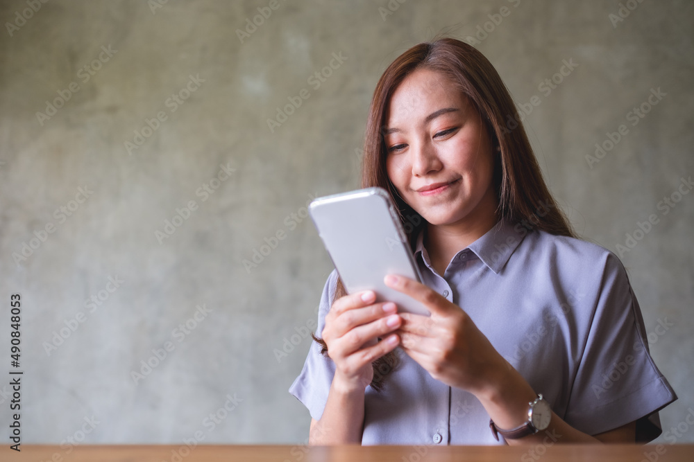 Portrait image of a beautiful young asian woman holding and using mobile phone Portrait image of a beautiful young asian woman holding and using mobile phone