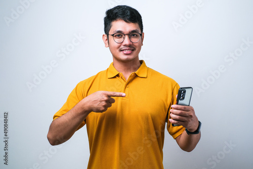 Asian man using smartphone wearing casual shirt ivery happy pointing with hand and finger