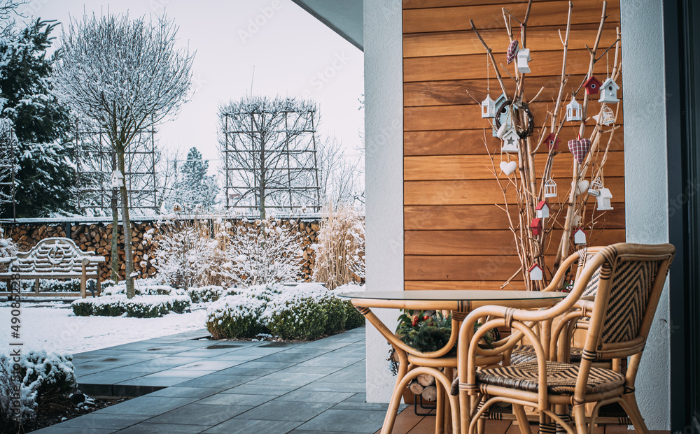 Fototapeta premium Taras zimą z meblami ogrodowymi i zaśnieżoną ławeczką angielską. 