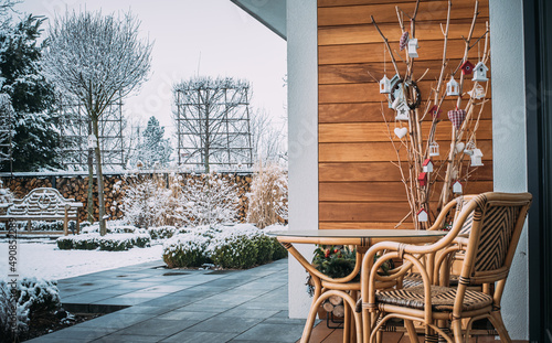 Taras zimą z meblami ogrodowymi i zaśnieżoną ławeczką angielską. 
