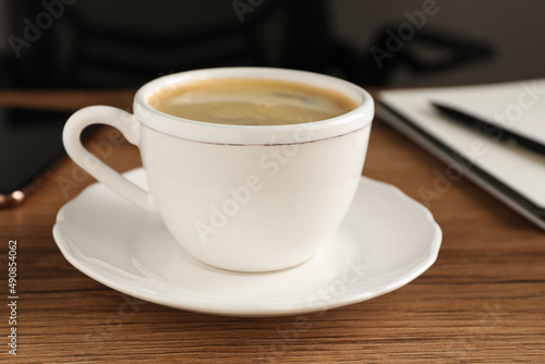 Cup of americano on wooden table in office, closeup. Coffee Break