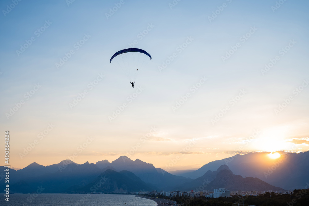 Silhouette of a man on a paraglider flying over the sea at sunset. Silhouette of a man on a paraglider flying over the sea at sunset.