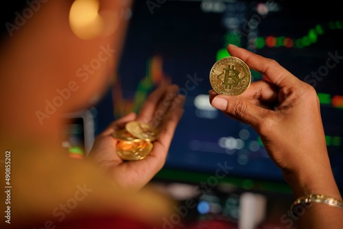 Bitcoin gold coins in the hands of a stockist with blurry chart background The concept of virtual currency photo