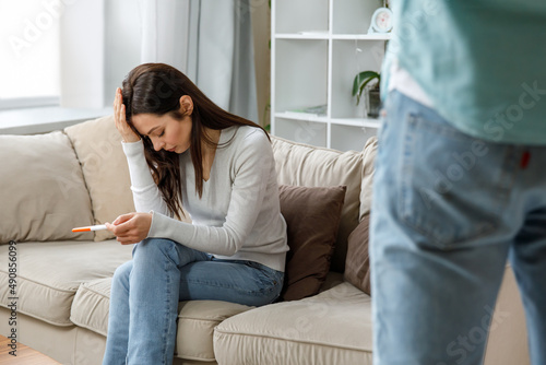 A sad young woman holds a pregnancy test in her hand. The concept of unwanted pregnancy.