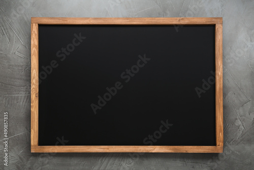 Clean black chalkboard with wooden frame on grey background